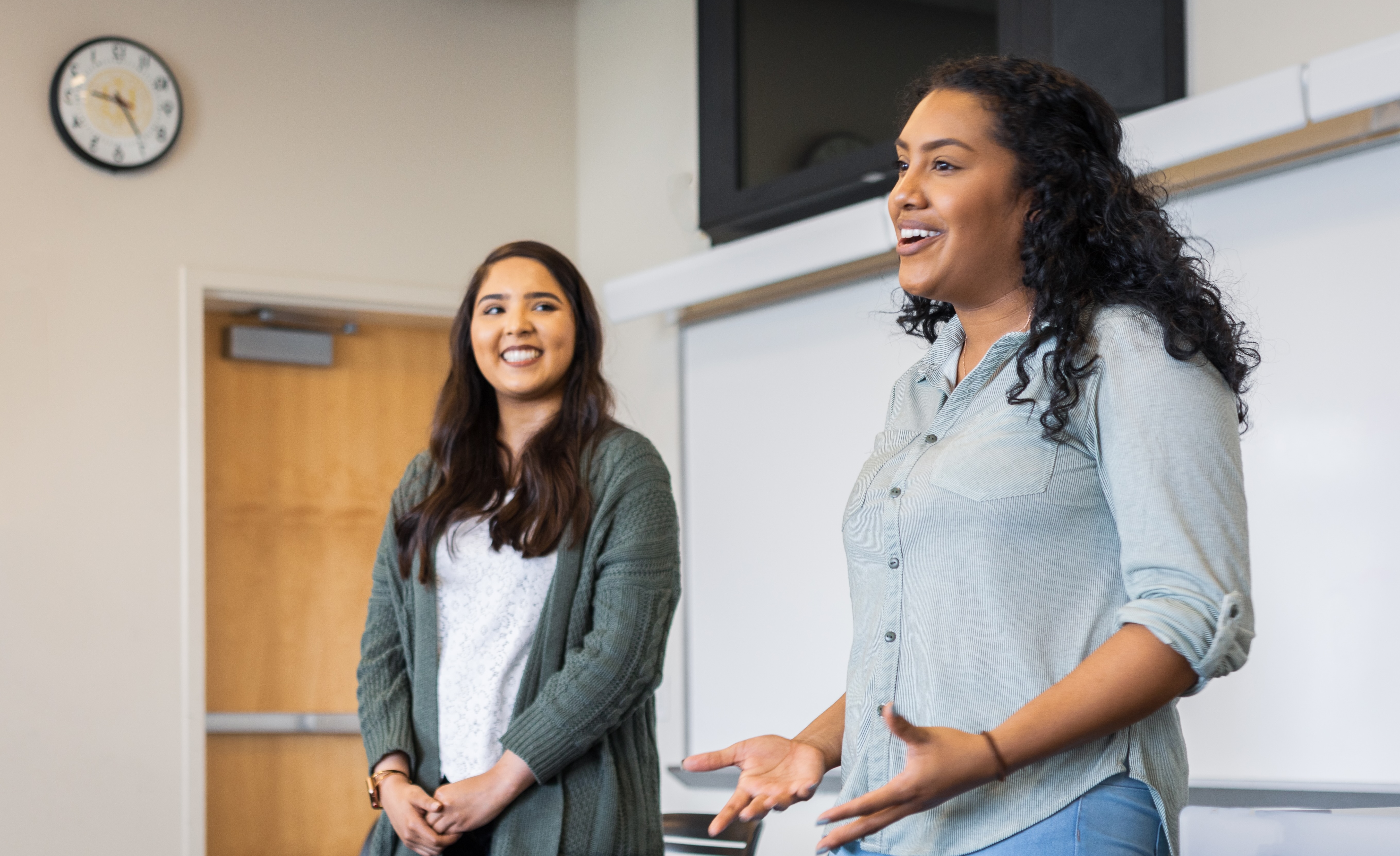 two female students speaking to a classroom